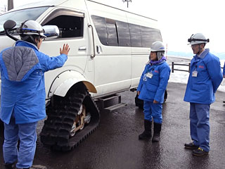 クローラー車の説明を受ける神津さん［右から2人目］